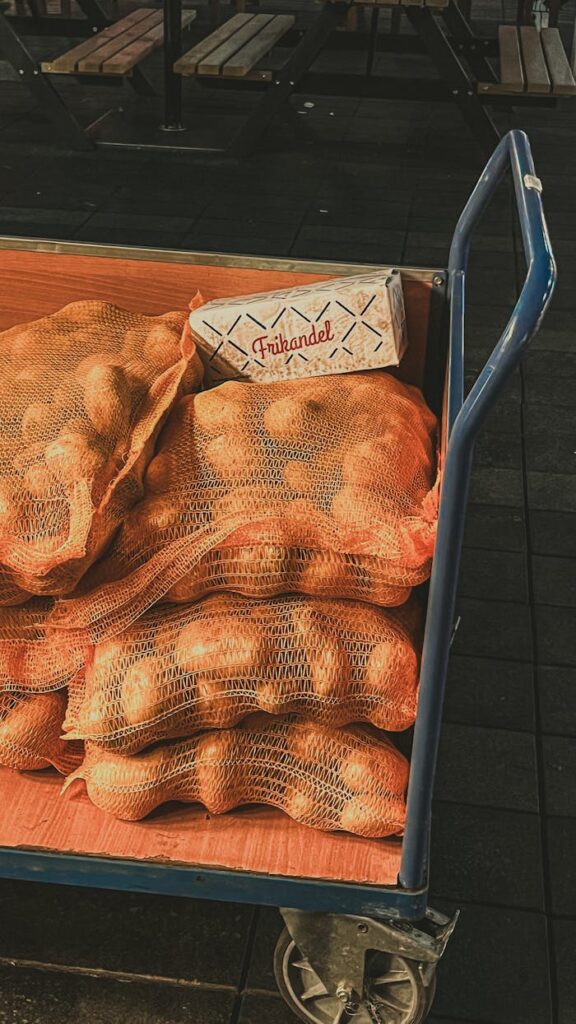 A cart carrying sacks of potatoes and a frikandel box at a market.